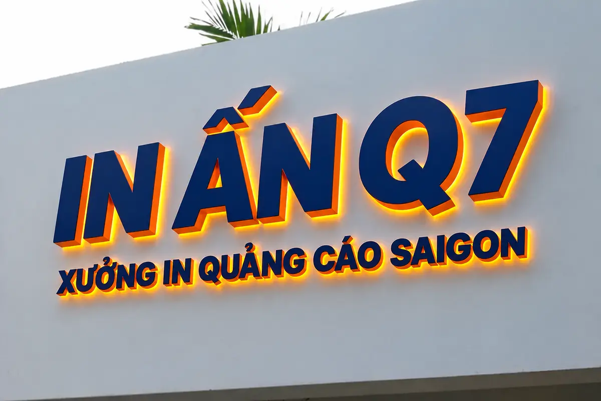Chữ nổi mica In Quảng Cáo Q7 màu xanh navy và cam được lắp trên tường mặt tiền thực tế.