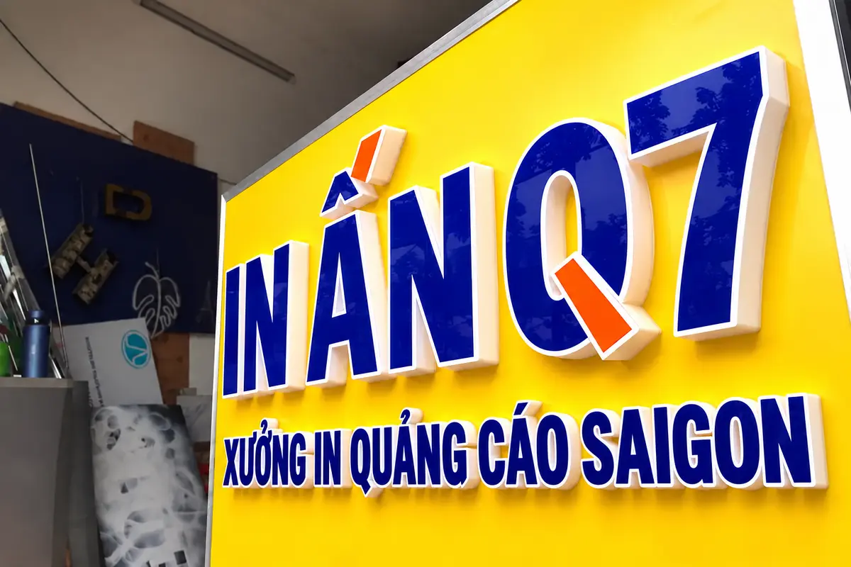 Bảng hiệu chữ nổi mica trên nền vàng tại mặt tiền cửa hàng thực tế.
