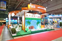Gian hàng du lịch màu cam xanh, bảng hiệu Miền di sản diệu kỳ, hình minh họa du lịch và khu tiếp khách.