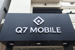 Bảng hiệu nền Alu màu đen gắn chữ nổi bạc Q7 Mobile trên mặt tiền cửa hàng.