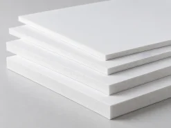 Các tấm Formex trắng chưa in xếp so le, lộ cạnh và độ dày tấm.