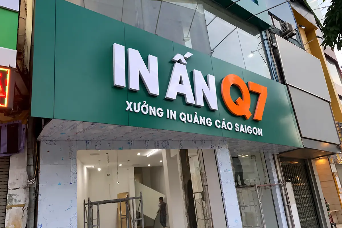 Kỹ thuật viên lắp chữ mica trên mặt tiền xanh trong quá trình thi công.