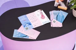 Tờ gấp giới thiệu sự kiện tông hồng xanh đặt trên bàn tròn