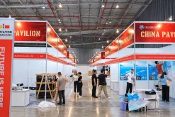 Lối đi giữa các gian hàng China Pavilion màu đỏ trắng, có nhân sự và vật dụng phục vụ lắp đặt.