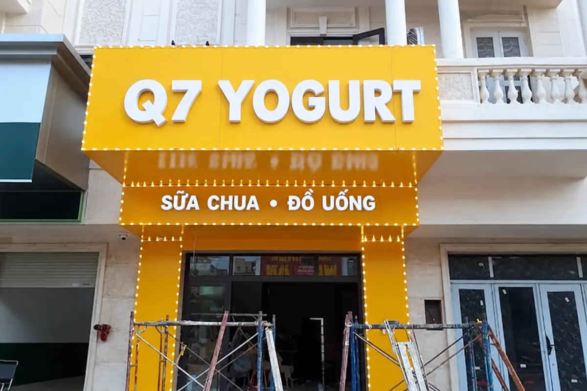 Mặt tiền cửa hàng ốp Alu vàng có chữ nổi và đèn viền, giàn giáo vẫn đặt tại công trình.