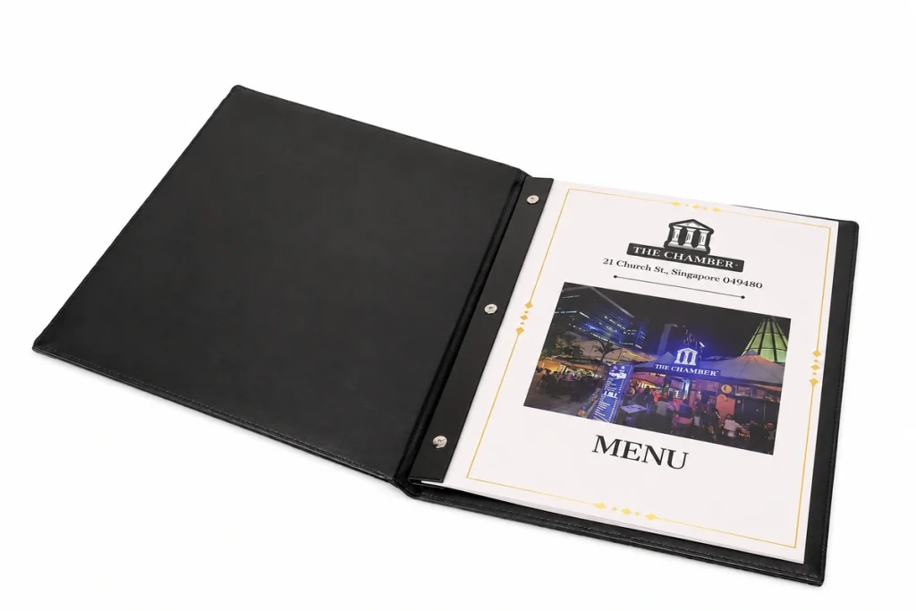 Menu bìa đen mở ra, lộ nẹp ba ốc cố định các tờ ruột in màu.